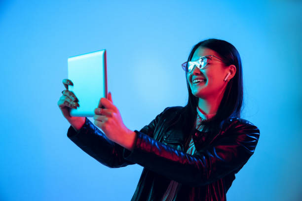 istock Beautiful girl's facial expression in neon light on blue studio background 1164899685