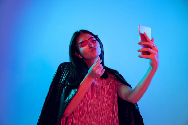istock Beautiful girl's facial expression in neon light on blue studio background 1164899696
