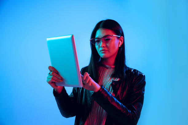 istock Beautiful girl's facial expression in neon light on blue studio background 1164899697