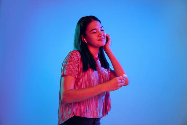 istock Beautiful girl's facial expression in neon light on blue studio background 1164899763