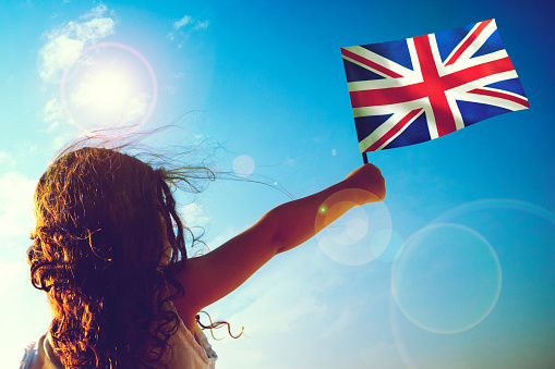Little girl waving English flag on sunny beautiful day