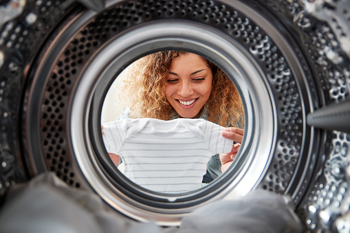 View Looking Out From Inside Washing Machine As Woman Takes Out Baby Clothes