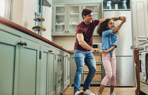 Practising for their daddy-daughter ball Shot of a young man dancing with his daughter in the kitchen at home dancing dad stock pictures, royalty-free photos & images