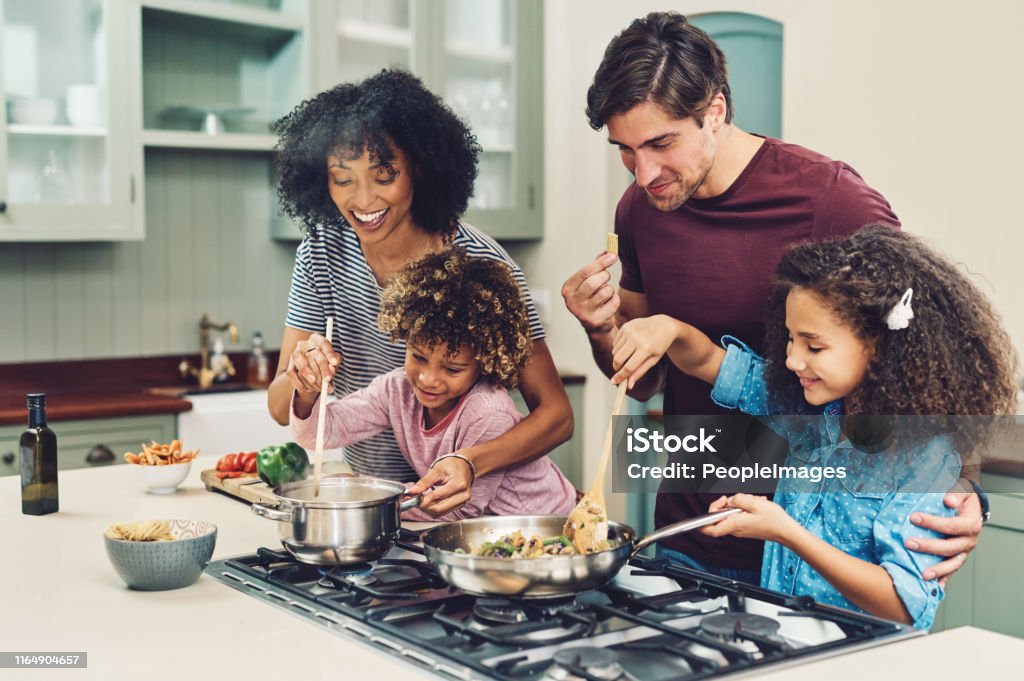 A meal cooked by the whole family tastes better Shot of a family of four cooking together in their kitchen at home Family Stock Photo