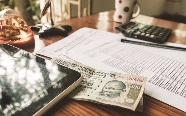 インドの通貨は、ペン、電卓、お金、机の上に置かれたアプリケーションフォームの隣のテーブルの上にあります。 - stock certificate investment savings certificate ストックフォトと画像