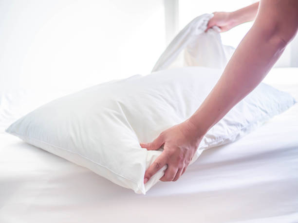 biała poduszka na łóżku w sypialni z kobietą rękę, którzy robią pokój. - sheet human hand bed women zdjęcia i obrazy z banku zdjęć