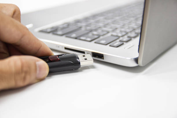 istock hand man hold Flash drive connect to USB port plug-in computer laptop for transfer data 1164917254