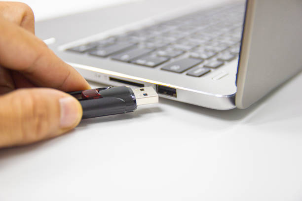 istock hand man hold Flash drive connect to USB port plug-in computer laptop for transfer data 1164917333
