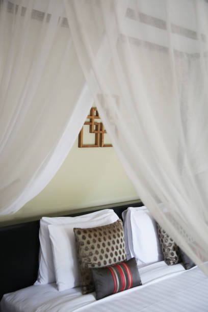 istock Bed with white linen, pillows and mosquito net. Vintage Interiors. Bed with canopy net. 1164920947