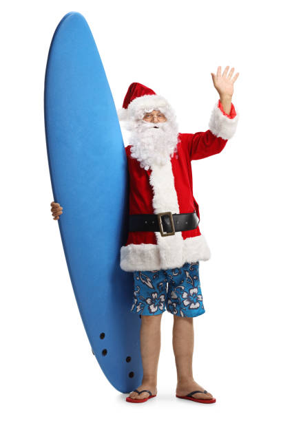 feliz santa claus en unas vacaciones con una tabla de surf saludando a la cámara - santa claus waving christmas photography fotografías e imágenes de stock