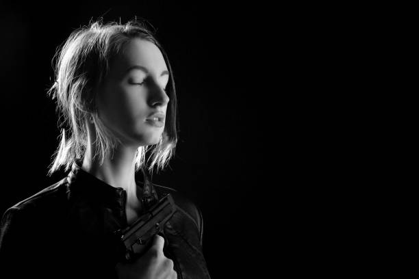 serious girl with gun on black background with copy space, monochrome