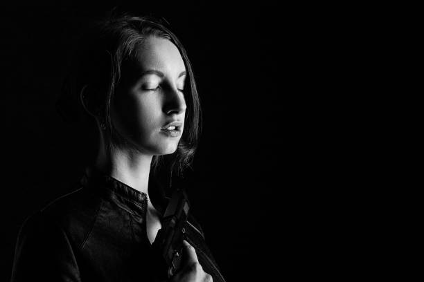 serious girl with gun on black background with copy space, monochrome