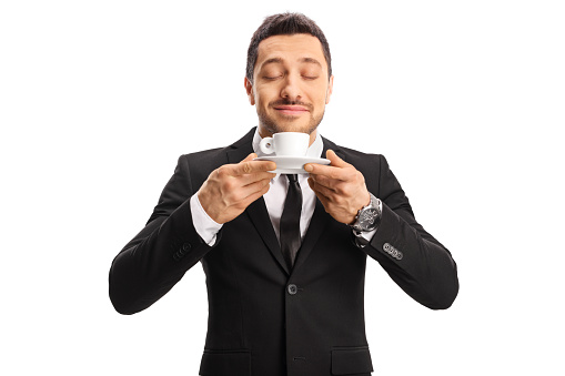 Young man in a suit enjoying the smell of a coffee isolated on white background