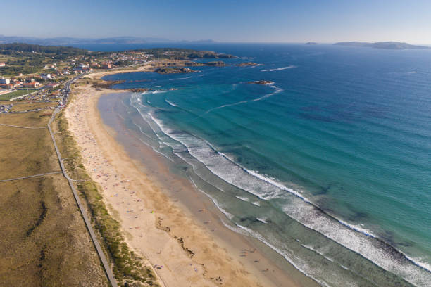 istock ocean waves, sandy beach with people bathing in the water, view from drone, Lanzada beach, Galicia, Spain 1164930273