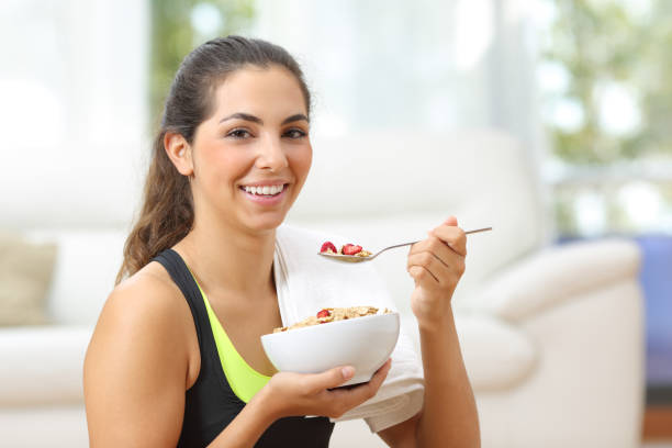 sportswoman posing with cereals after sport at home - eating women breakfast cereal imagens e fotografias de stock