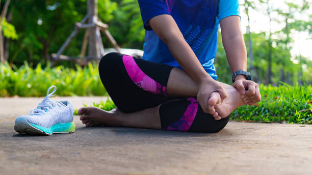 junge frau hält knöchel unter schmerzen auf der stadionbahn. gebrochene verdrehte gelenk-laufsportverletzung. athletische frau berührt fuß wegen verstauchung. gesundes konzept - running marathon jogging track event stock-fotos und bilder