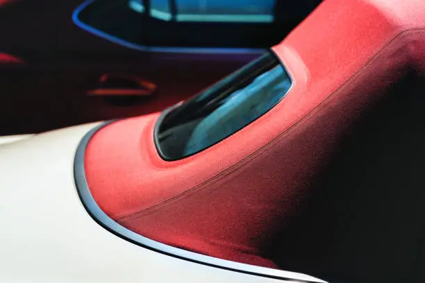 Cabriolet with a red rag soft red roof with a window on the background of the car on a summer day