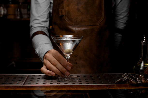 istock Bartender holding glass with martini on counter 1164935249