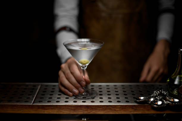 istock Bartender holds glass with martini on counter 1164935290
