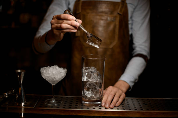istock Bartender puts ice in cocktail glass with tongs 1164936563