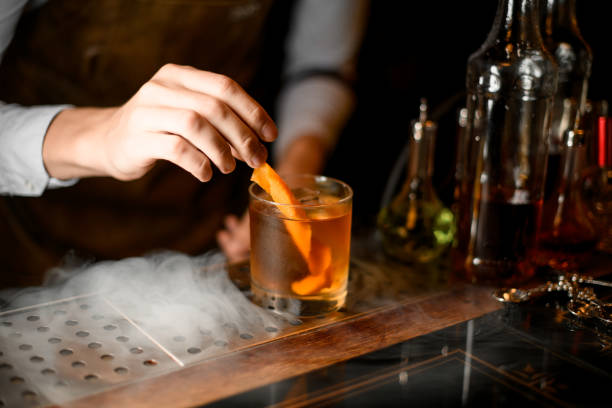 istock Bartender puts orange zest in whiskey glass 1164936574