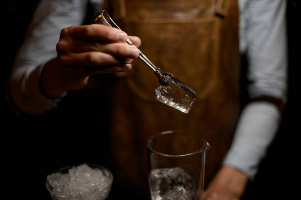 istock Bartender putting ice in cocktail glass with tongs 1164936580