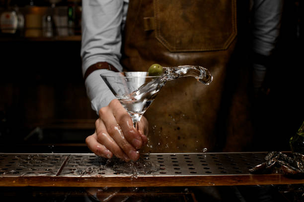 istock Bartender shaking up glass with martini on counter 1164937198