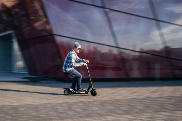 istock Young man on electric scooter on street 1164937301