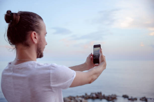 istock man photographing the sunset. 1164937891
