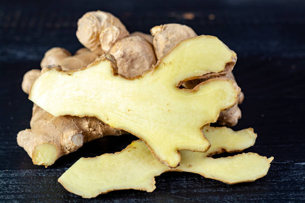 istock Fresh ginger roots close up on black wooden background 1164939351
