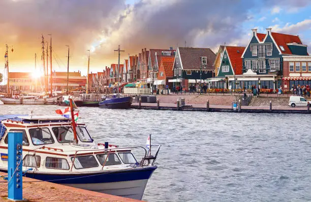 Volendam, Netherlands. Luxury yacht parked by pier in bay of North Sea on evening sunset under traditional old town.