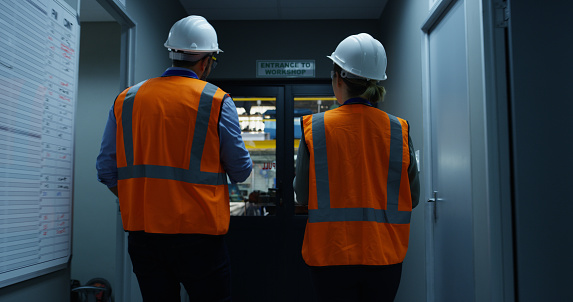 Rearview shot of two engineers walking through an industrial place of work