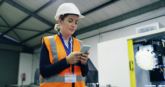 Shot of a young engineer using a smartphone in an industrial place of work