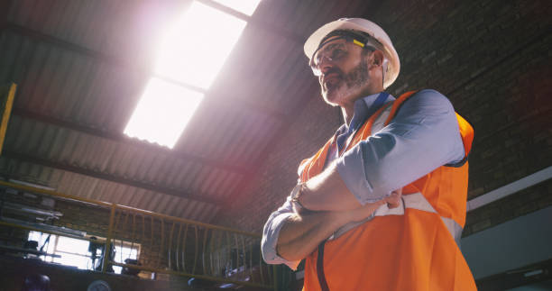 The all seeing eyes of an engineer Low angle shot of a confident mature engineer in an industrial place of work reflective clothing photos stock pictures, royalty-free photos & images