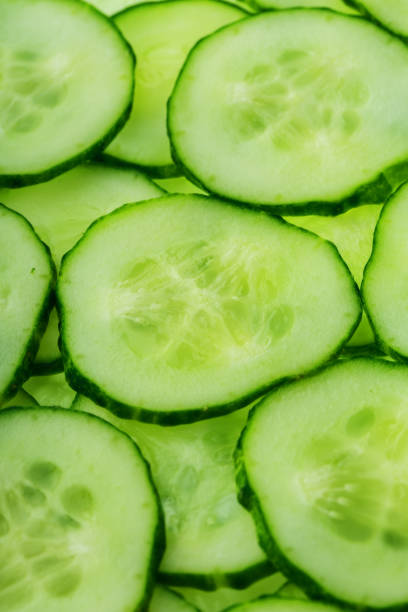 istock Slices of green fresh cucumber backlit as a textural background 1164943609