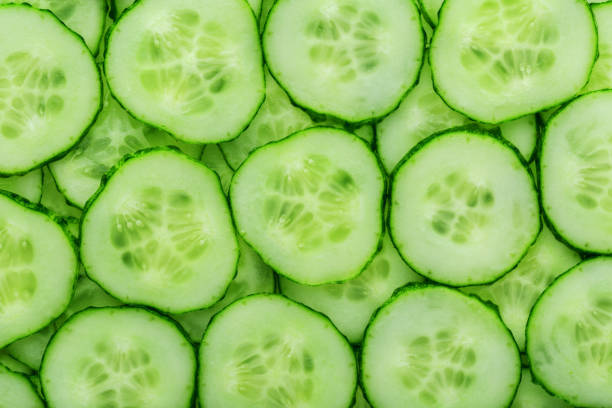 istock Slices of green fresh cucumber backlit as a textural background 1164943898