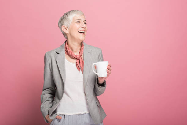 Woman drinking coffee and smiling Happy mature business woman holding cup of coffee and laughing womens issues stock pictures, royalty-free photos & images