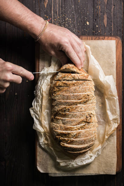 istock Hands cutting a loaf of bread on baking paper 1164949901