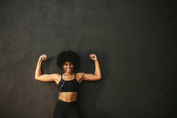 atleta mujer fuerte flexionando los músculos - human muscle women bicep girl power fotografías e imágenes de stock