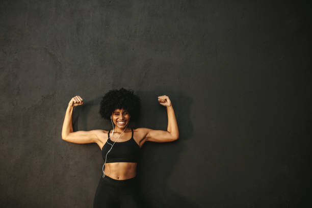 istock Strong female athlete flexing muscles 1164950573