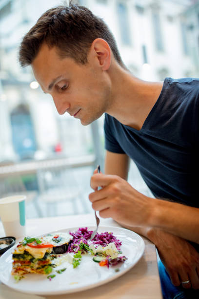 istock Young man eating salad in a cafe 1164950826