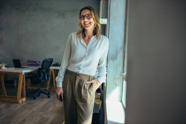istock Smiling businesswoman standing in office 1164952759