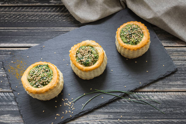 three puff pastry containers filled with spinach puree with sesame seeds - vol au vent imagens e fotografias de stock