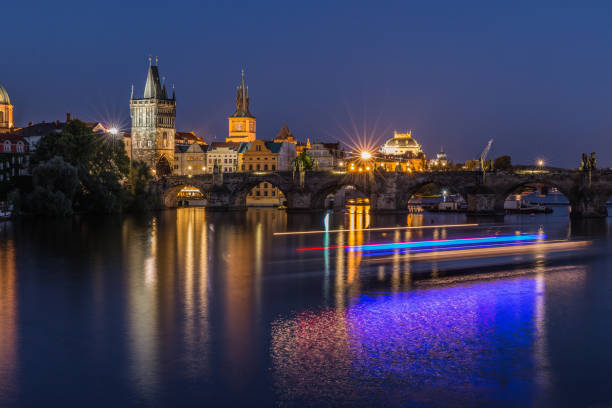 istock Charles Bridge and Old Town Tower at night with reflections on the Vltava and light from the boat 1164961621