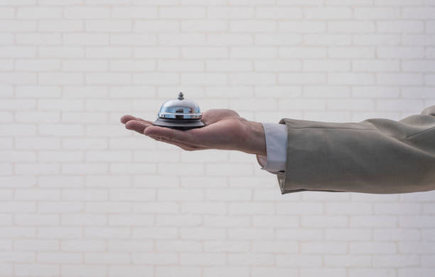 Hand in white gloves holding hotel bell