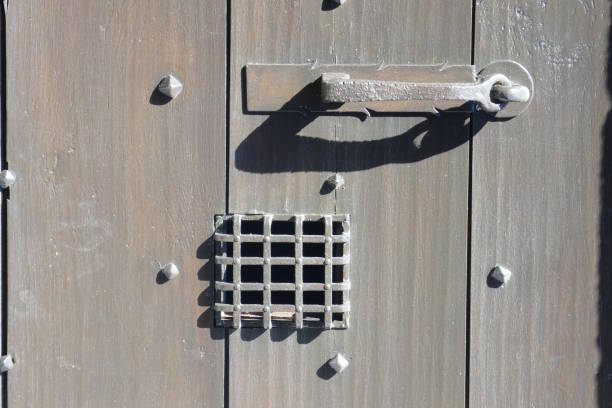 An old and worn doorhandle on a heavy hardwood door.