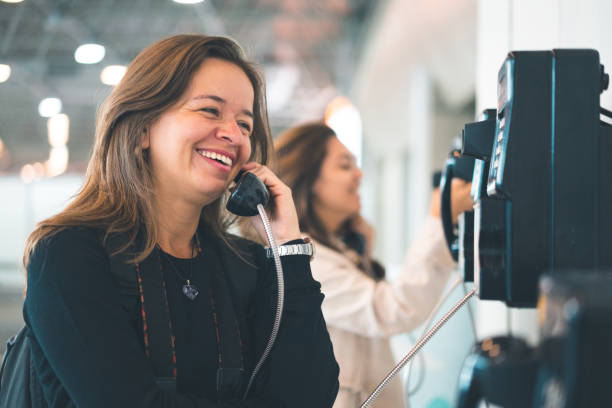 Woman talking at public telephone Using Phone, Adault, Obsolete, Talking pay phone on the phone latin american and hispanic ethnicity talking stock pictures, royalty-free photos & images