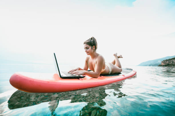 donna carina che gode della tecnologia moderna durante il paddle boarding - surfing the net foto e immagini stock