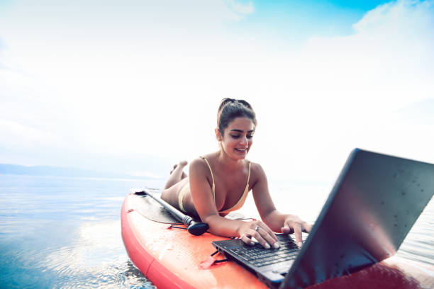 istock Female Working On Waterproof Laptop While Relaxing On Paddleboard In Lake 1164971042