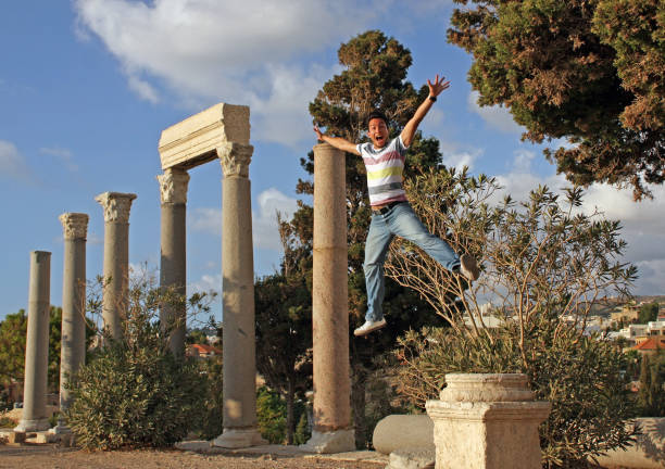 istock Happy young man jumping with arms raised 1164974754